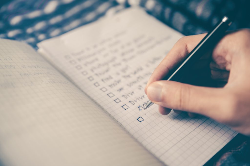 Person writing a checklist in notebook