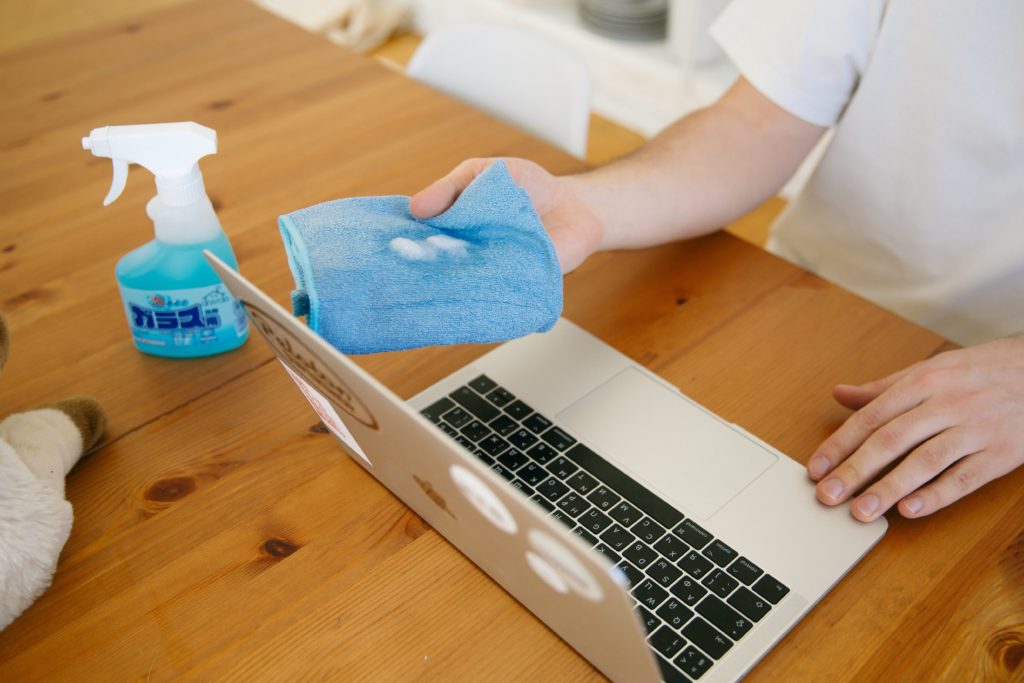 person disinfecting laptop