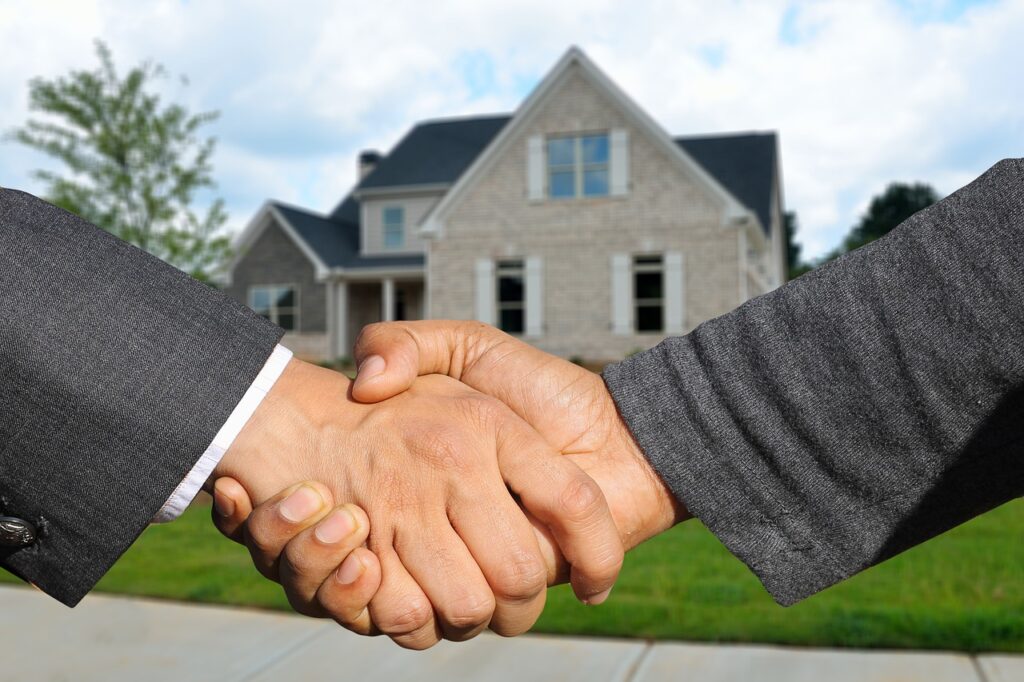 two men shaking hands in front of home