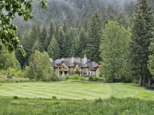 Luxury mansion on a golf course surrounded by forested mountains, evoking Sherwood Lake Club