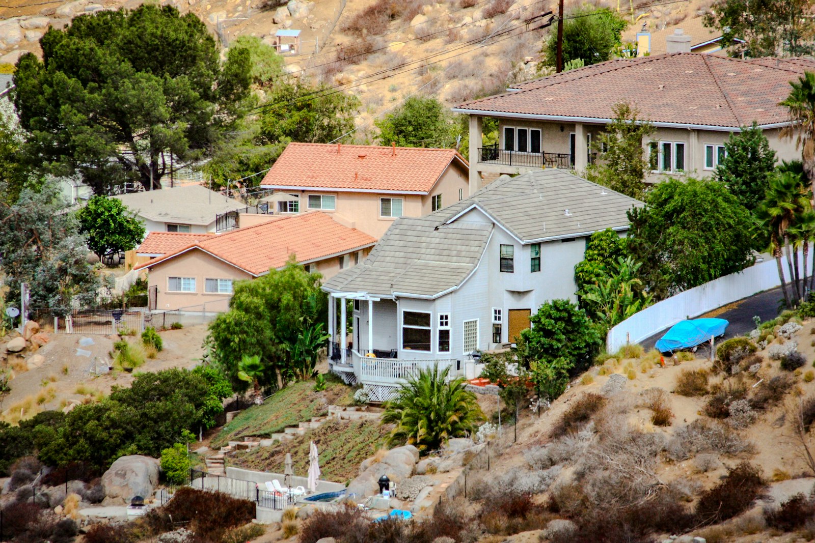 Tile roof homes built into a sunny hillside with mature trees, typical of Newbury Park view neighborhoods